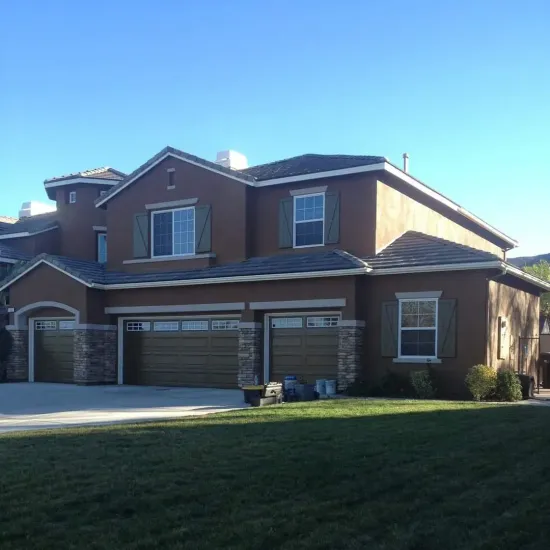 Two-story brick suburban house with a three-car garage and green lawn in daylight
