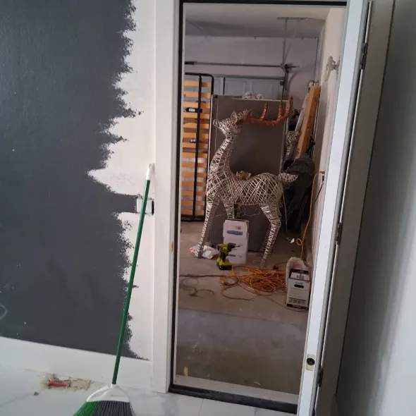 Partially finished room with a doorway, metal vent tubing, and construction materials on the floor.