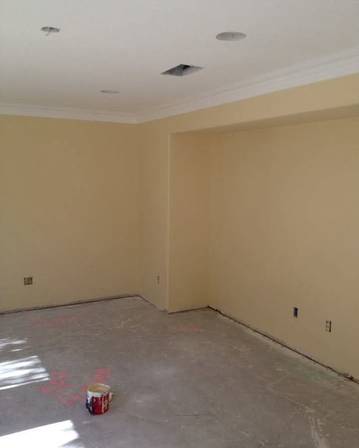 Empty beige room with unfinished floor, white ceiling, and a small paint can on the ground