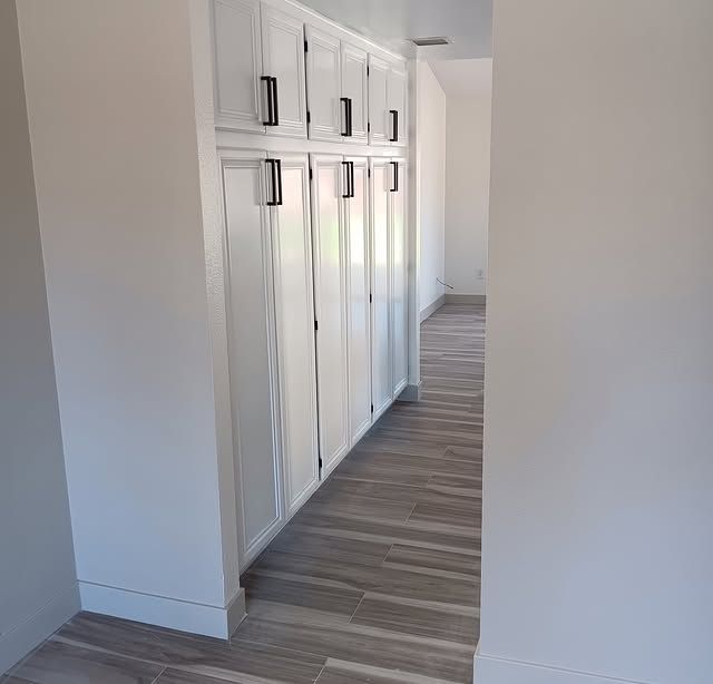 Hallway with white built-in cabinets and wood-look flooring