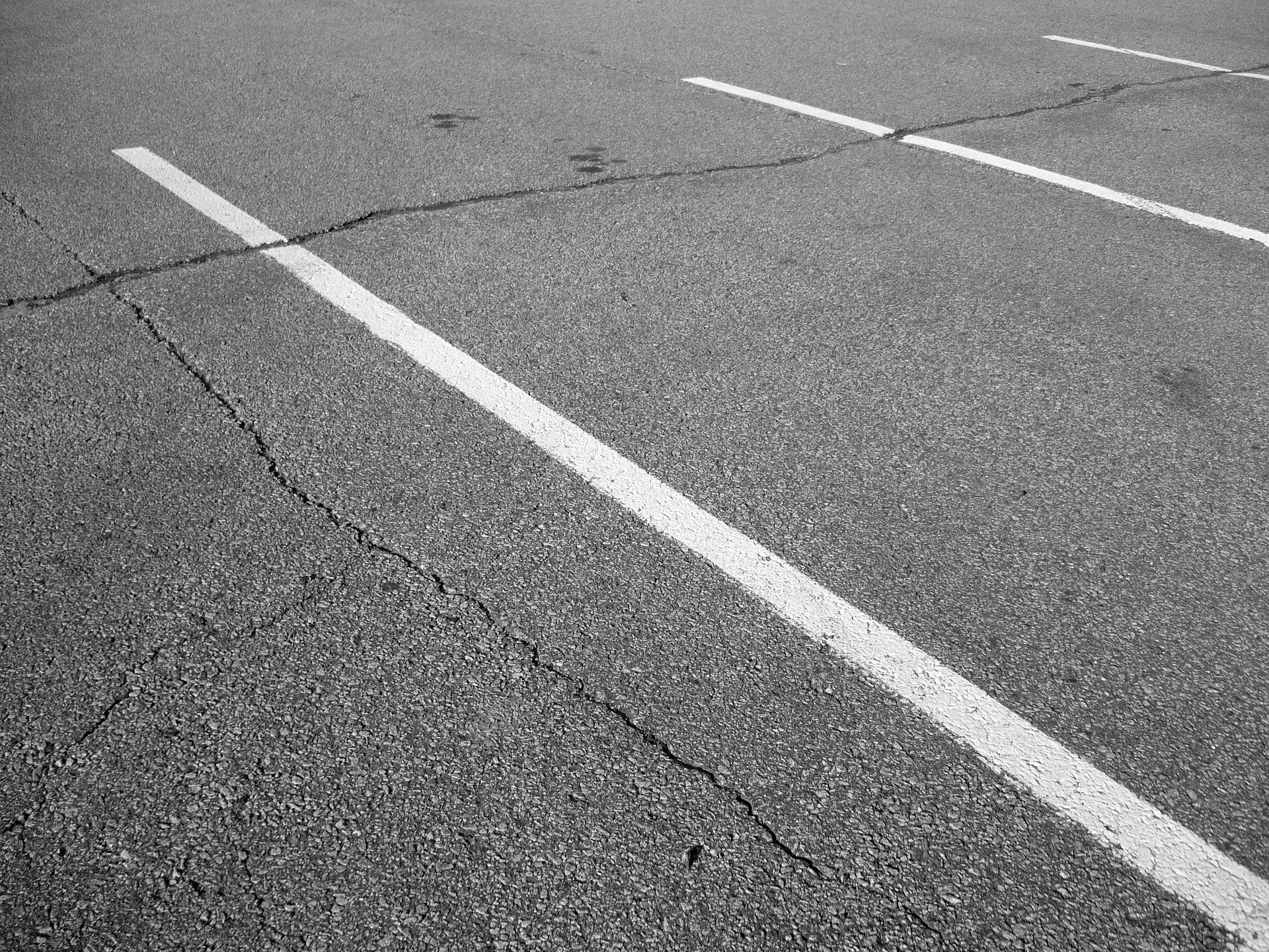 Cracked asphalt parking lot with white painted lines