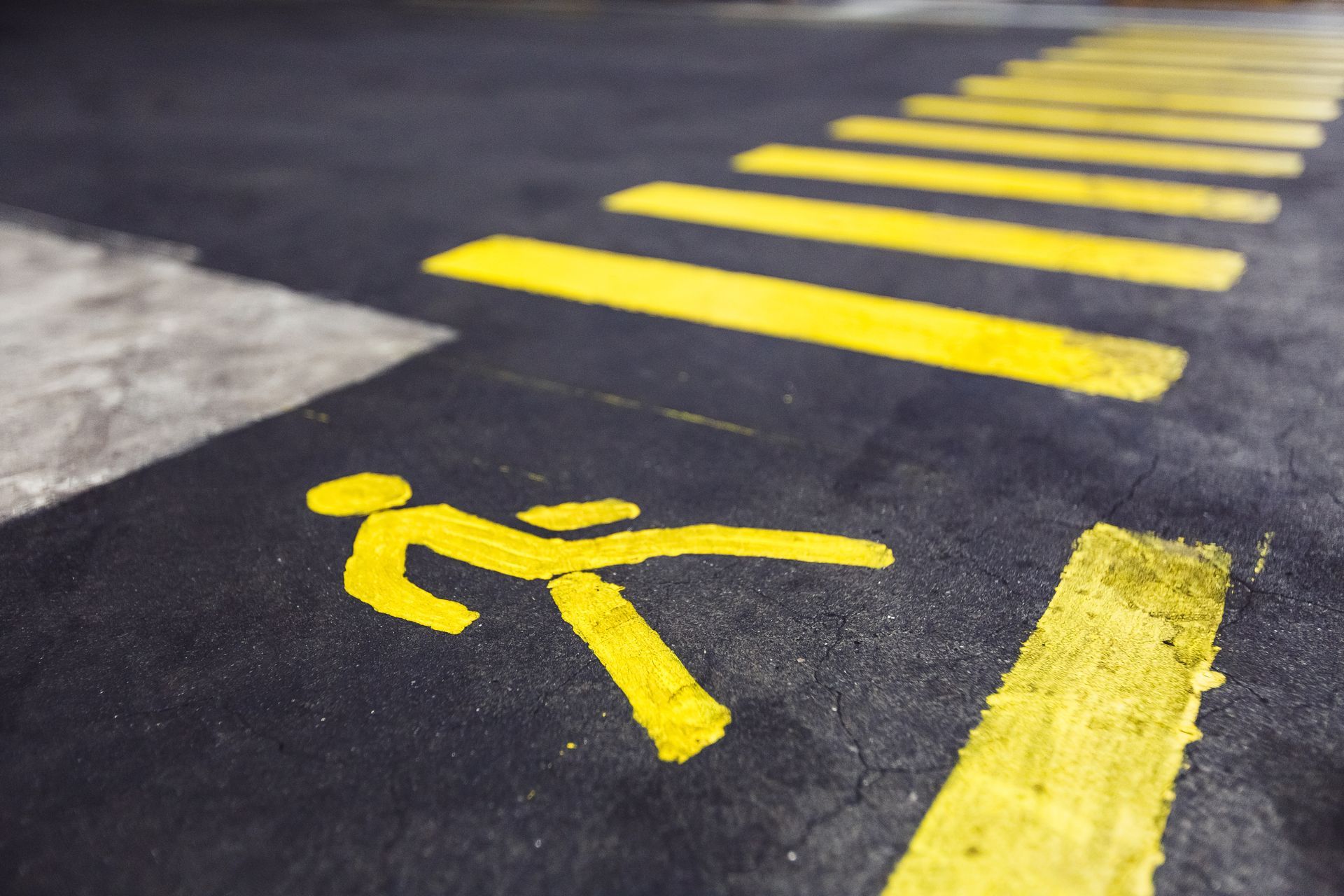 Yellow pedestrian crossing markings on dark pavement, viewed from a low angle