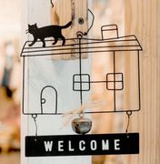 A welcome sign with a cat on top of a house