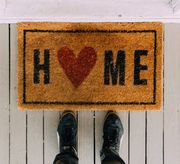A person is standing on a door mat that says home