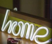 A neon sign that says home sits on a table