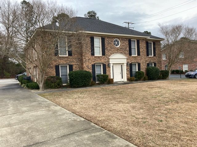 A large brick house with a black roof and white shutters