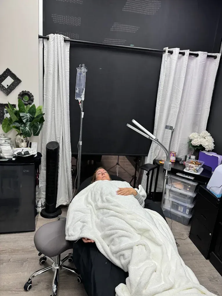 A woman is laying in a chair under a blanket in a room.