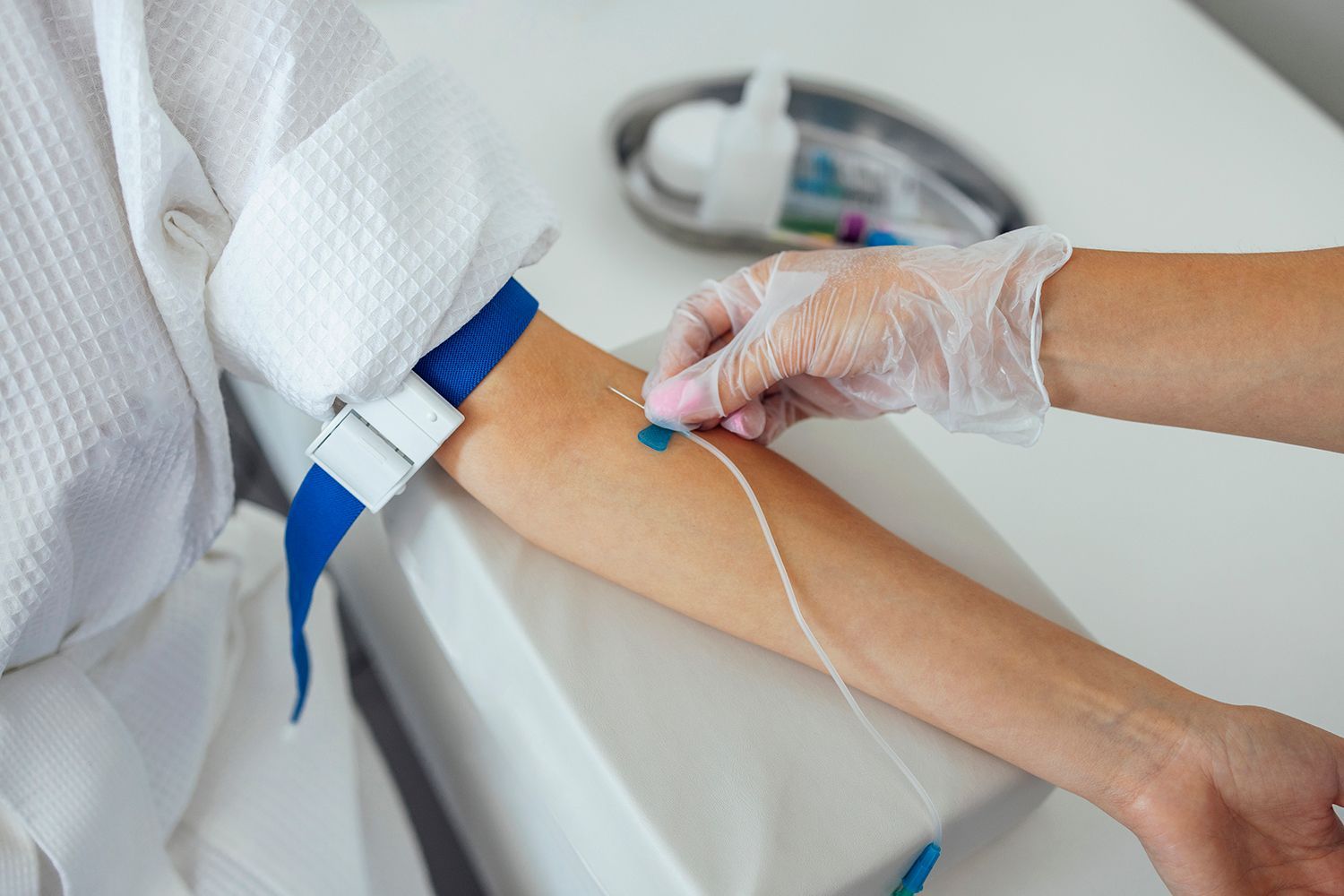 Healthcare worker inserting an IV catheter into a patient’s arm with a gloved hand