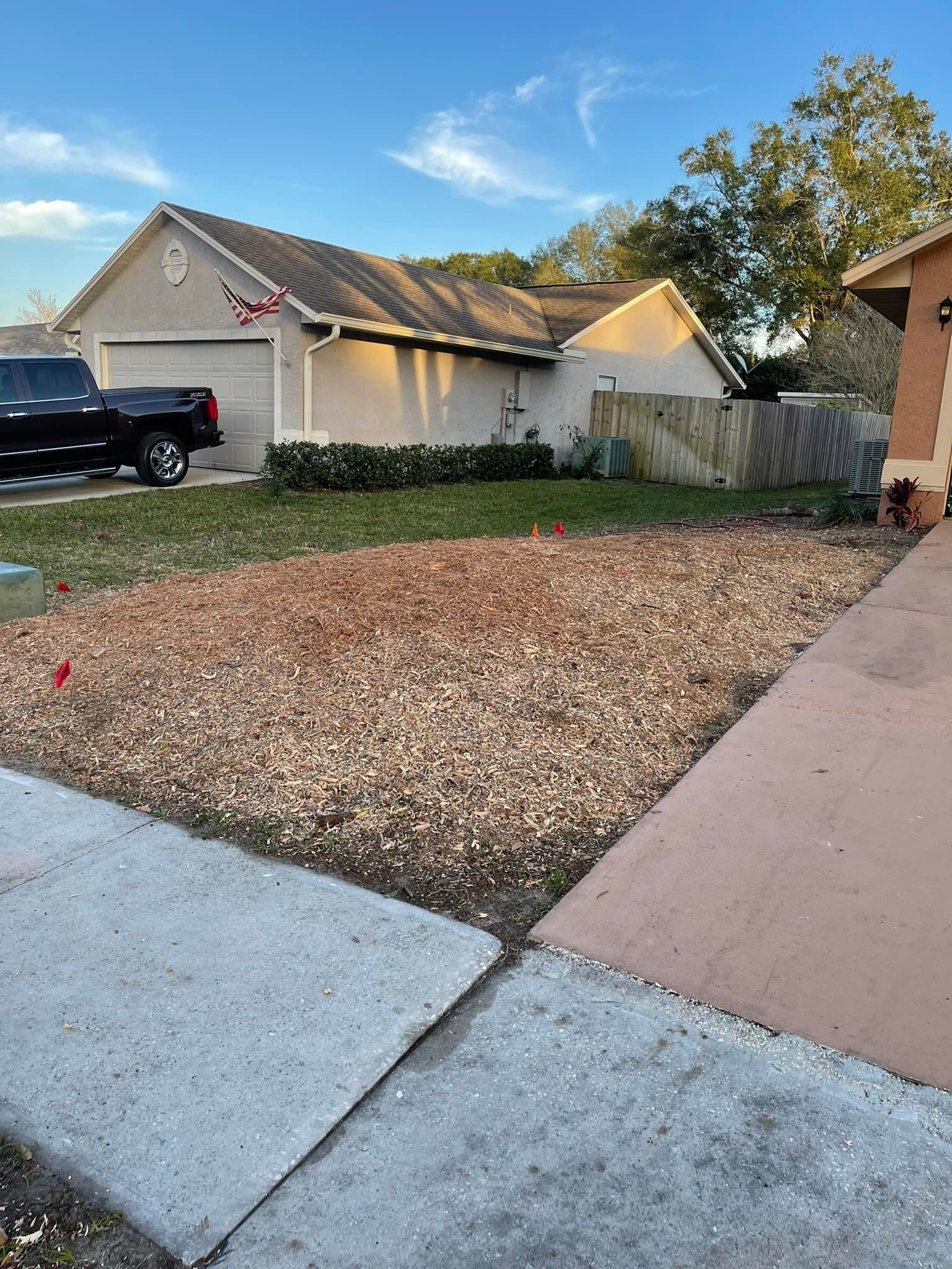 Front yard with gravel, a house, driveway, truck, and blue sky.