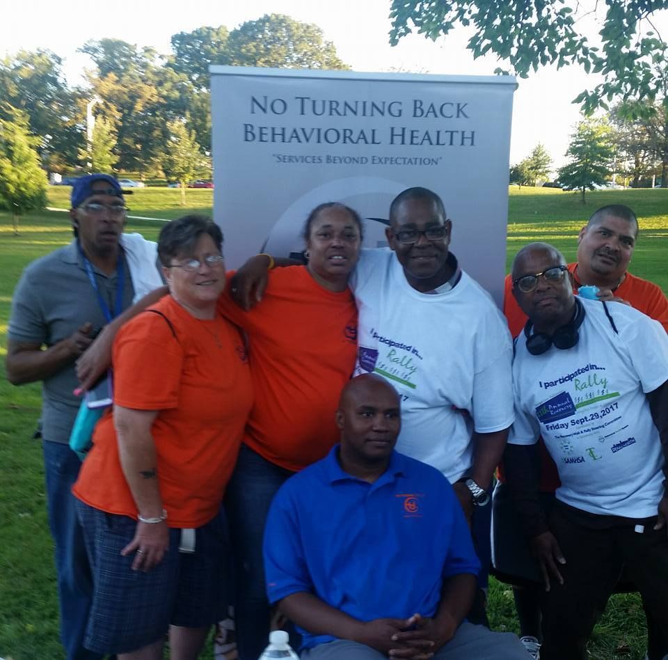 A group of people posing in front of a sign that says no turning back behavioral health