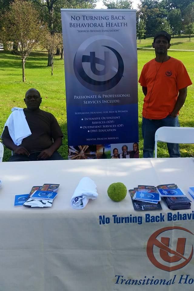 Two men standing in front of a table that says no turning back behavior
