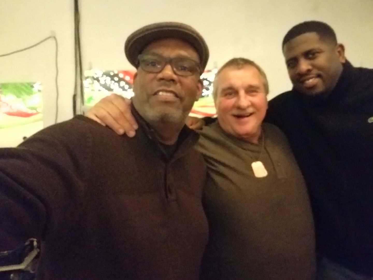 Three men posing for a picture with one wearing a hat