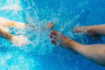 Swimmers’ arms slicing through bright blue water in a pool race