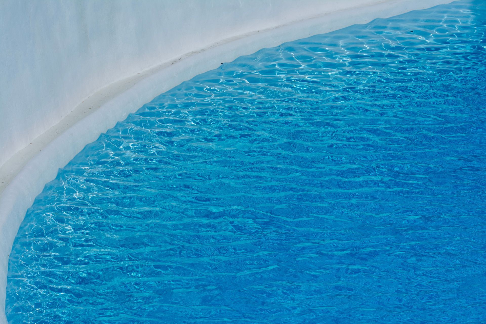 Blue water beside a curved white pool edge