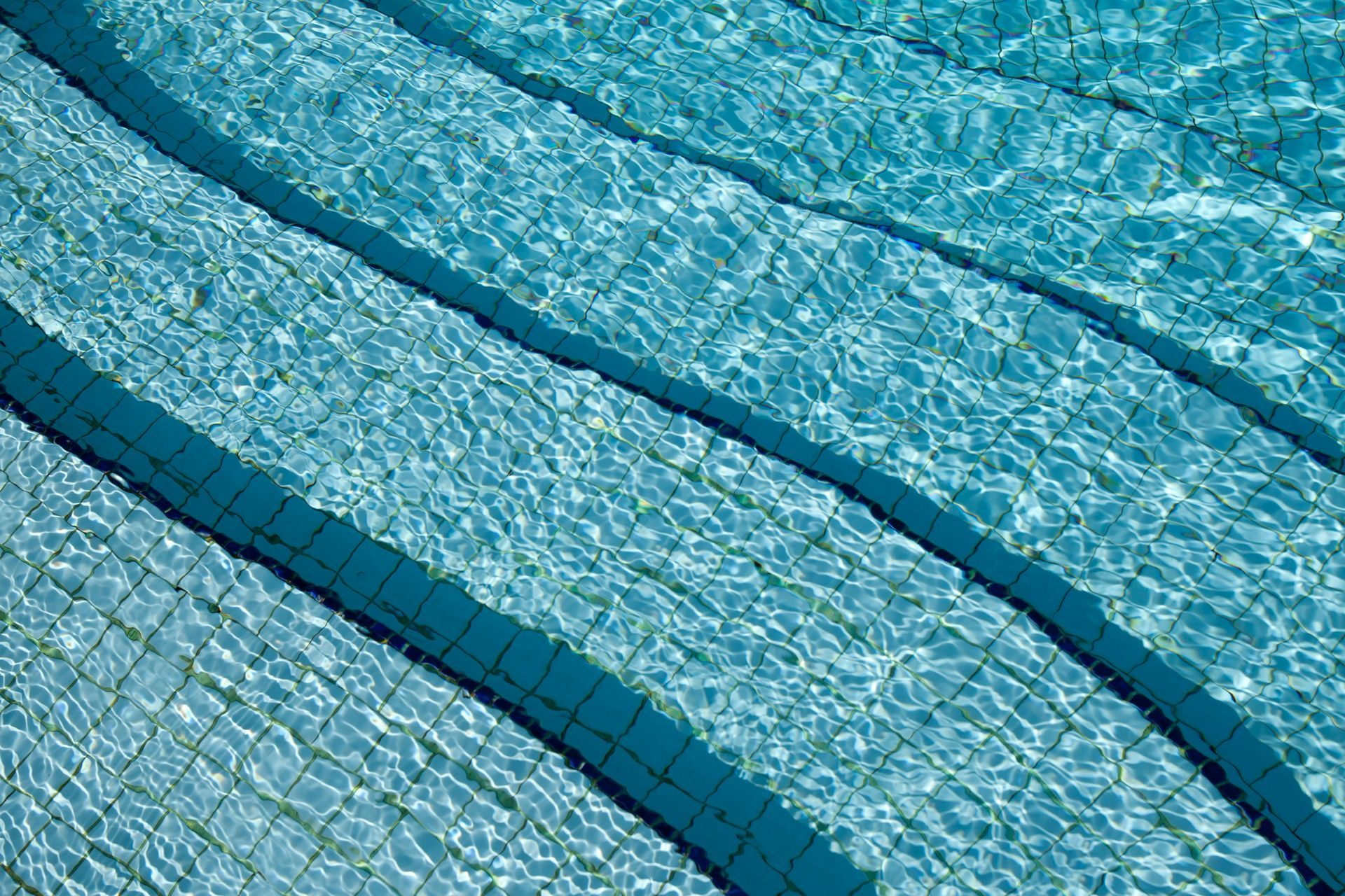 Blue swimming pool lanes with rippling water and dark lane dividers
