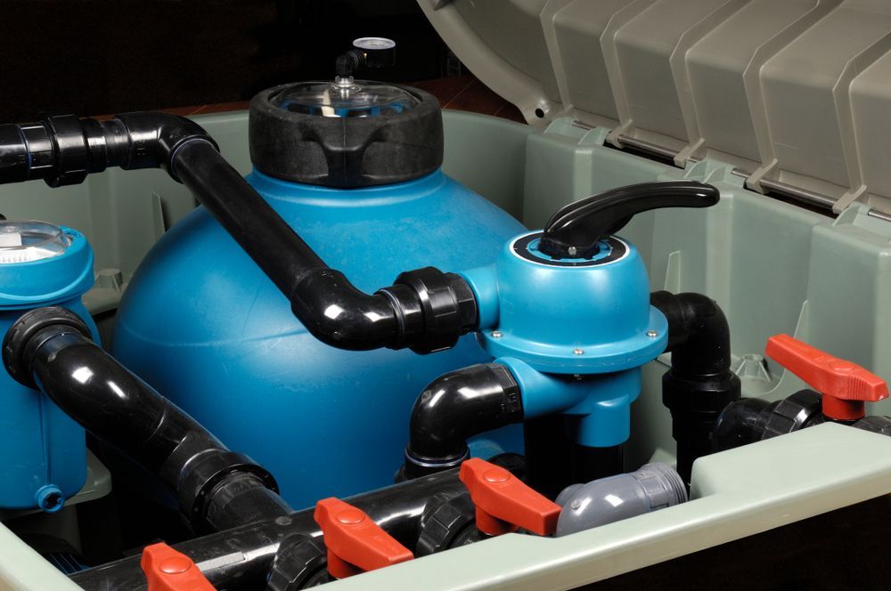 Close-up of a blue engine component with black hoses and red clips inside a compartment