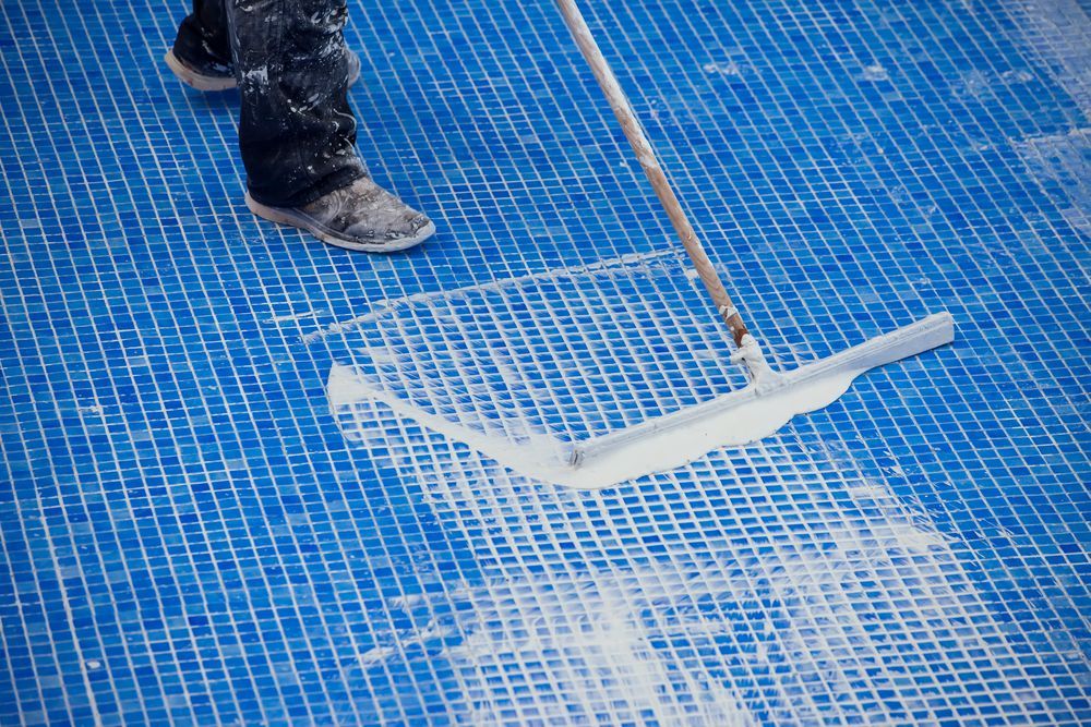 Black boot stepping near a white broken plastic piece on a blue tiled floor.