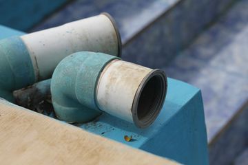 Blue and white plastic pipes stacked on a blue surface outdoors