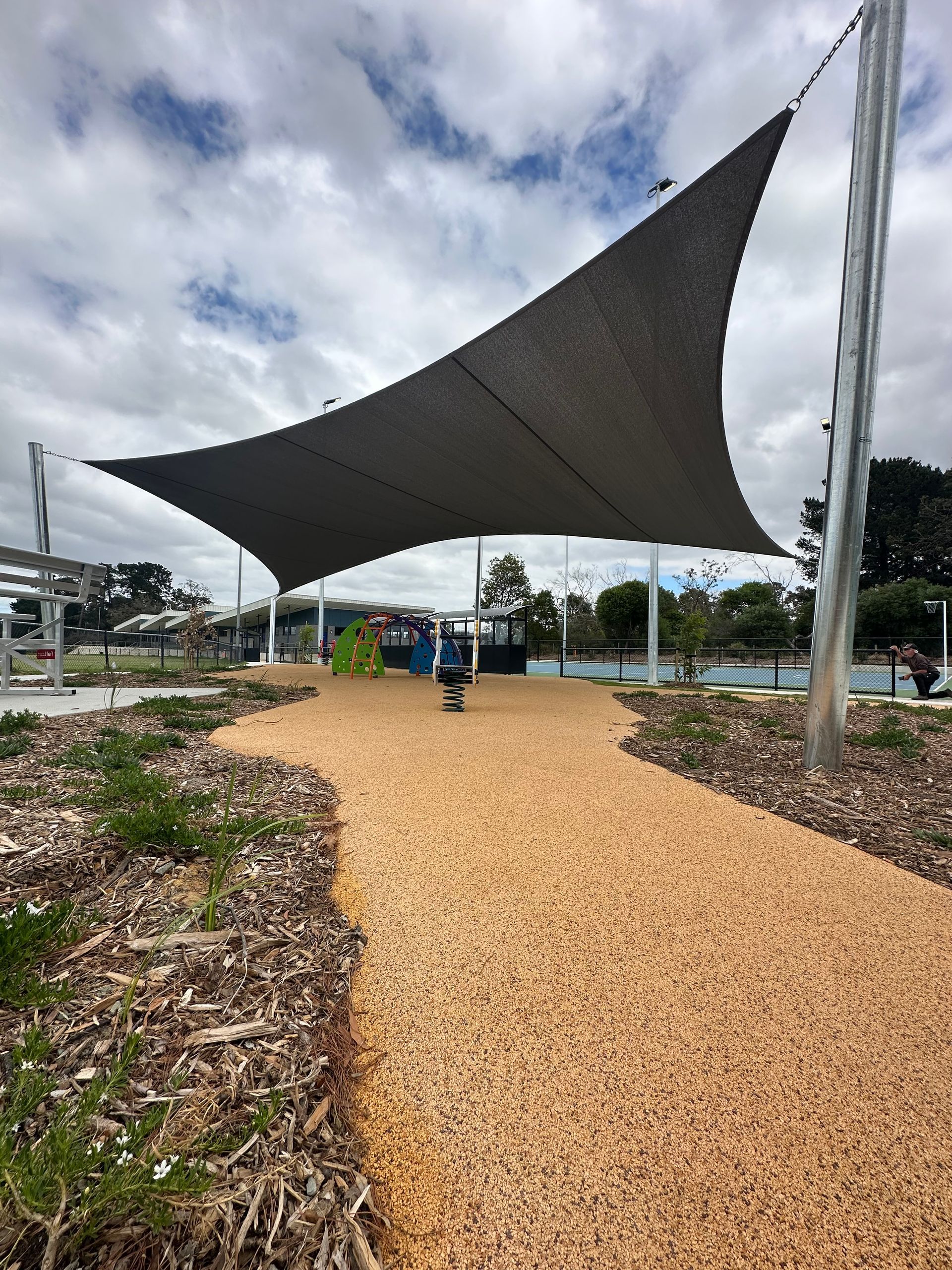 Large Commercial shade sail installation at Pearcedale Recreation Reserve in Melbourne, covering children’s playground with soft fall surface and spring rider, supported by galvanized steel posts, tensioned for safety and sun protection”