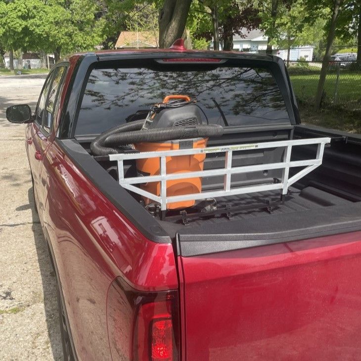 Red pickup truck bed with a white cargo rack holding an orange shop vacuum.