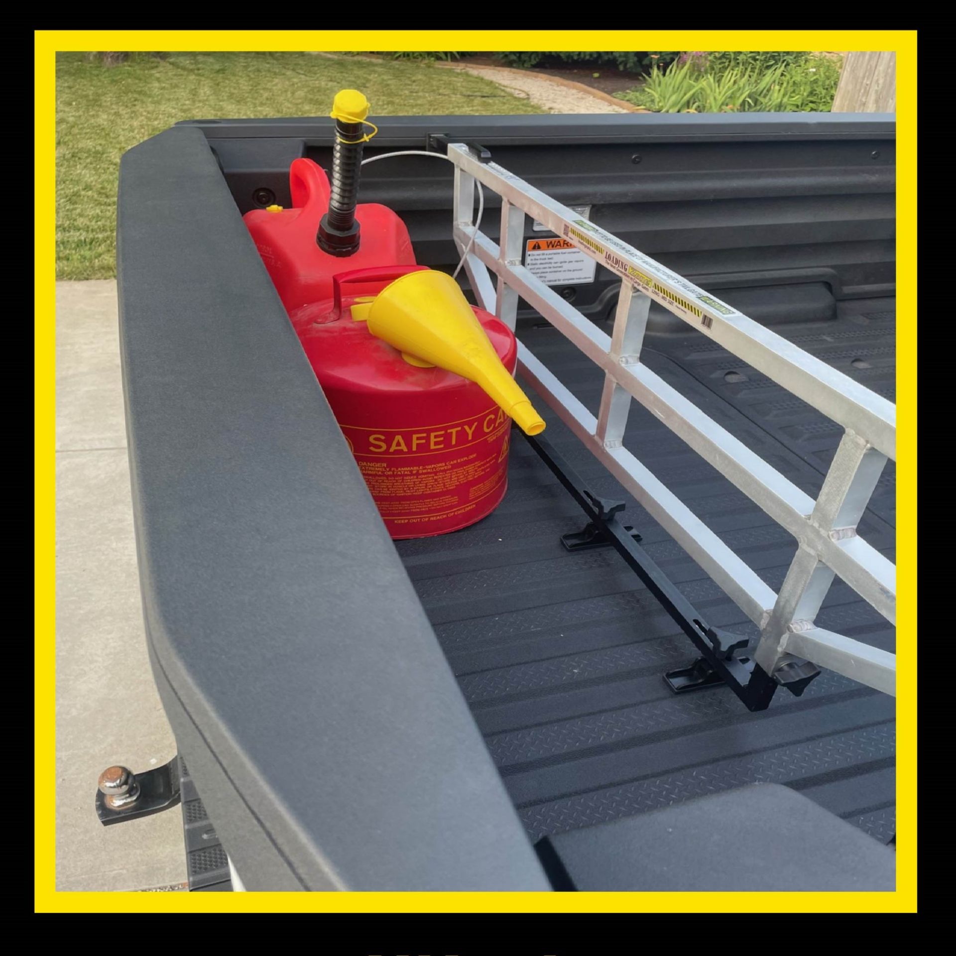 Red gas can and funnel in the bed of a black pickup truck with a white ladder-like bed extender.