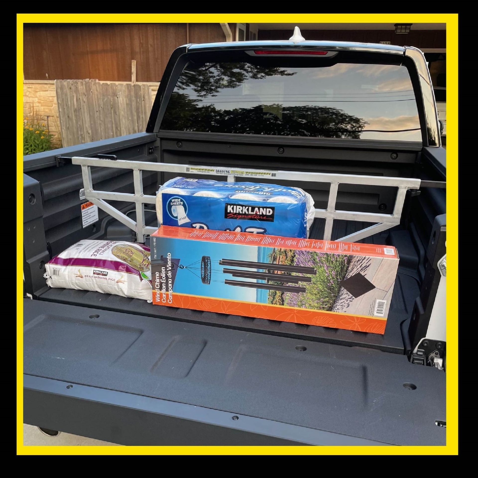 Truck bed with a cargo divider holding groceries and a long box.