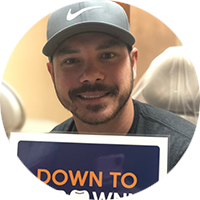 A man wearing a nike hat is holding a sign that says down to win