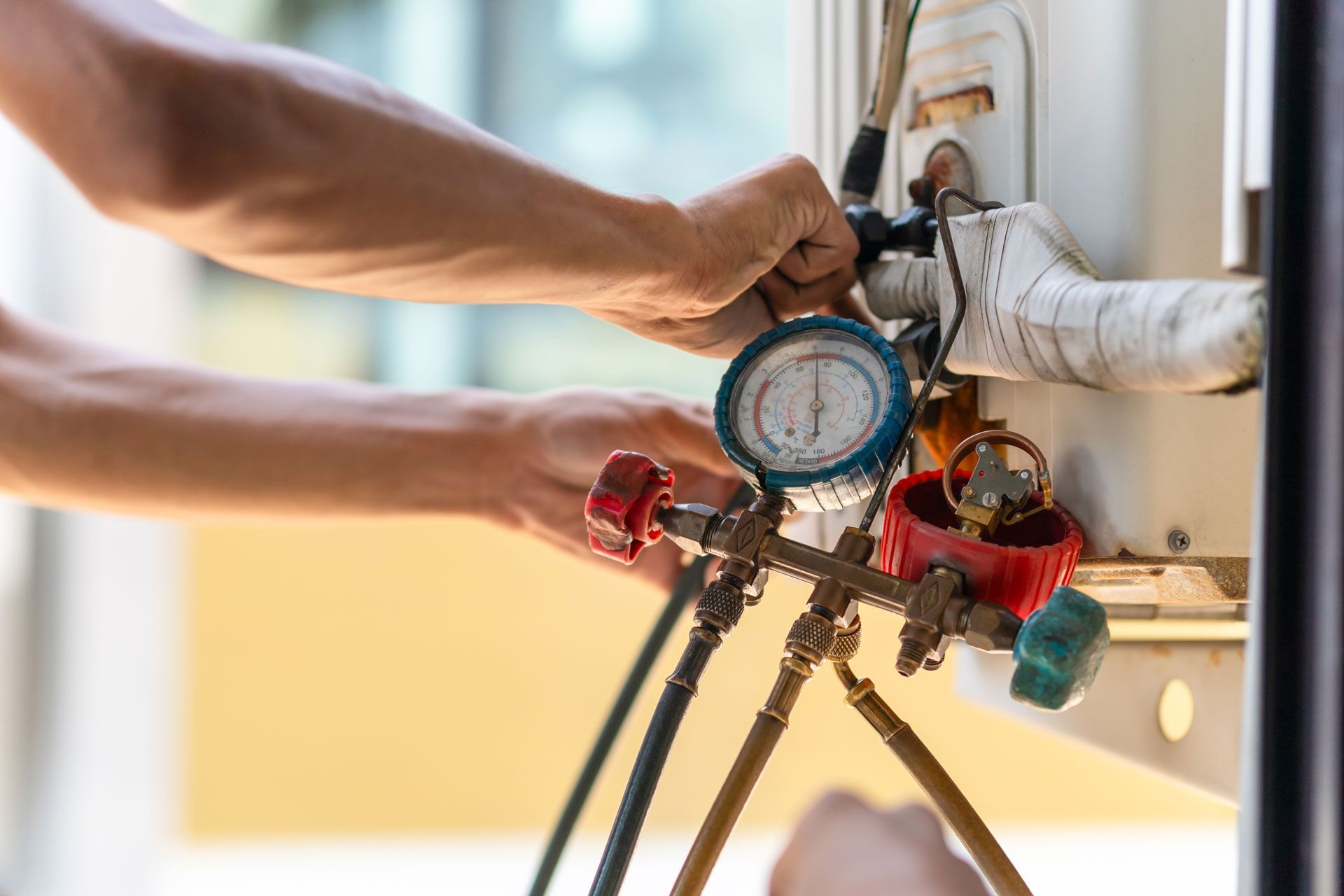 Hands adjusting gauges on an air conditioning unit.