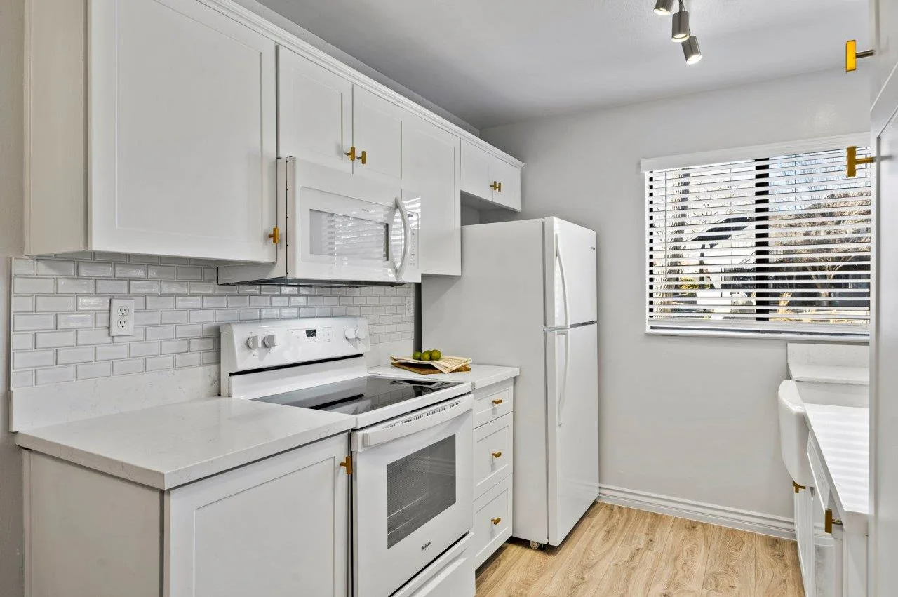 A kitchen with white cabinets , a stove , a refrigerator , a microwave , and a window at Ascent On Steamboat 