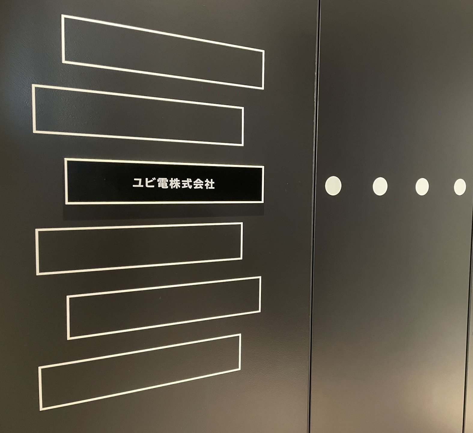 ユビ電株式会社の名前が表示されている壁
