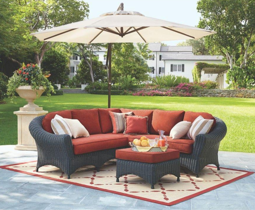 A patio with a sectional couch and an umbrella