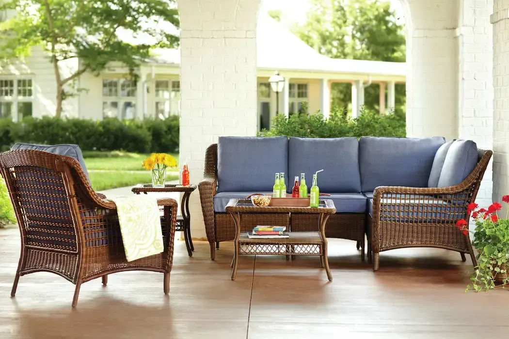 A porch with wicker furniture including a couch and chairs