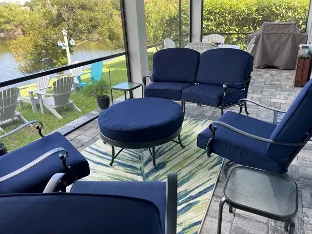 A screened in porch with blue furniture and a rug.