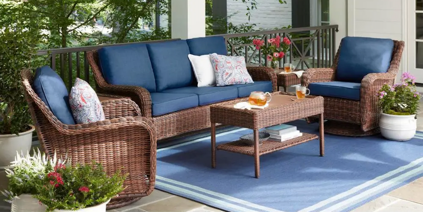 A patio with wicker furniture and a blue rug.
