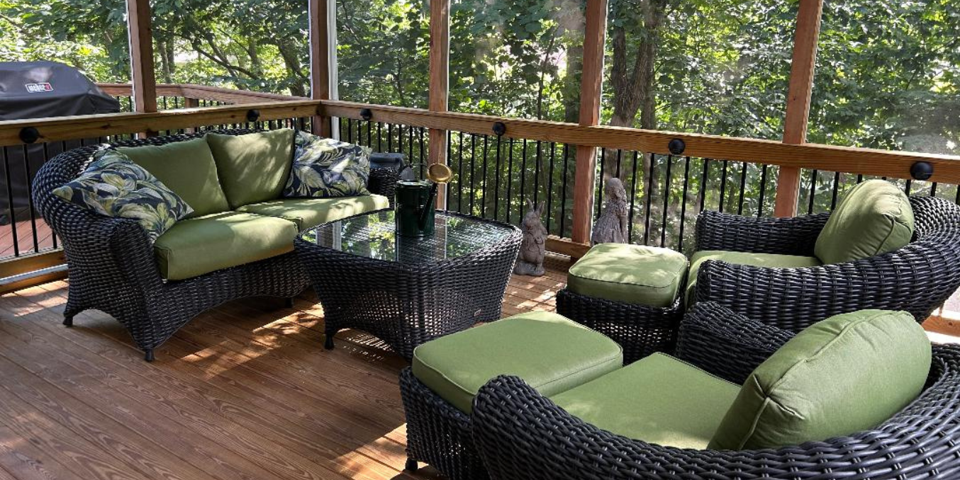 A screened in porch with wicker furniture and green cushions