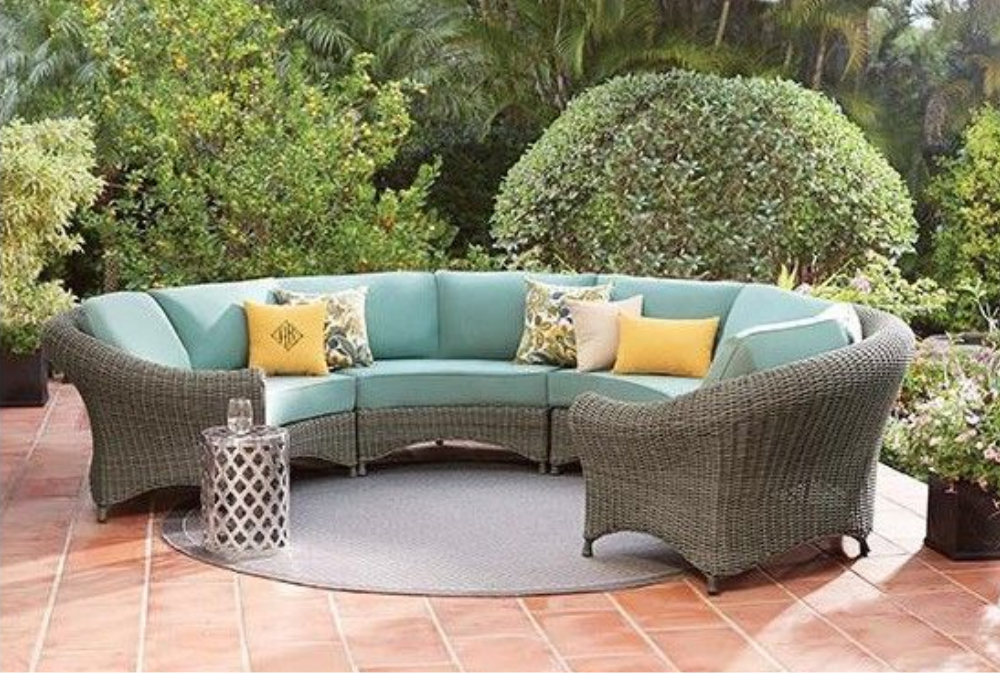 A patio with a wicker sectional couch and chairs