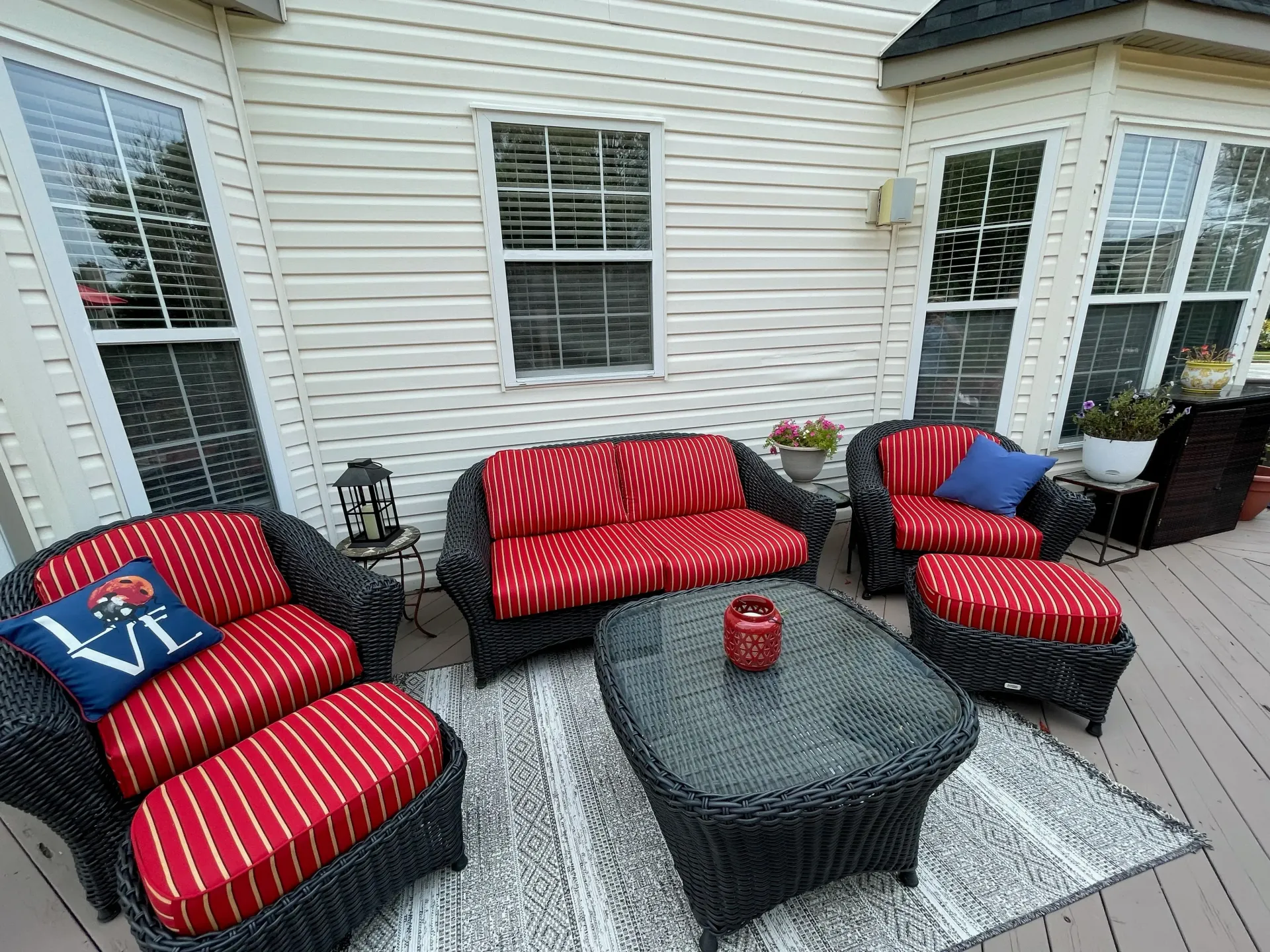 A patio with a couch , chairs , ottomans and a table.