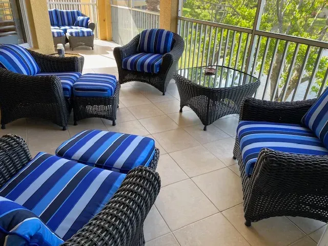 A balcony with wicker furniture and blue striped cushions