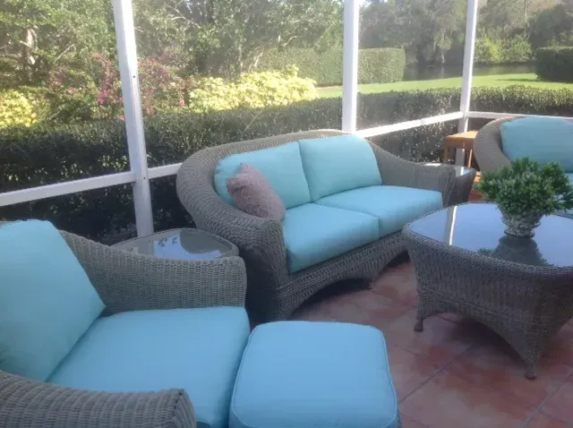 A screened in porch with a couch and chairs