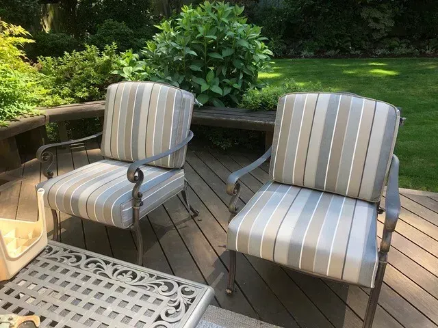 Two chairs and a table on a deck with a lawn in the background