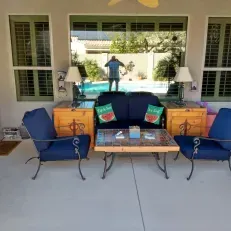 A patio with a couch , chairs , table and lamps.
