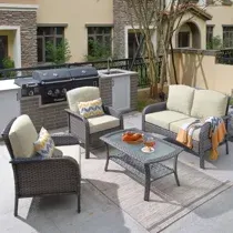 A patio with a couch , chairs , a table and a grill.