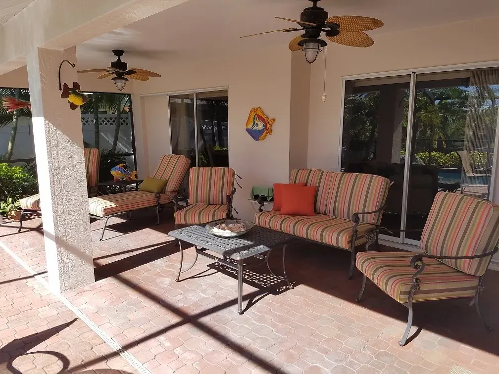 A patio with a couch and chairs and a ceiling fan