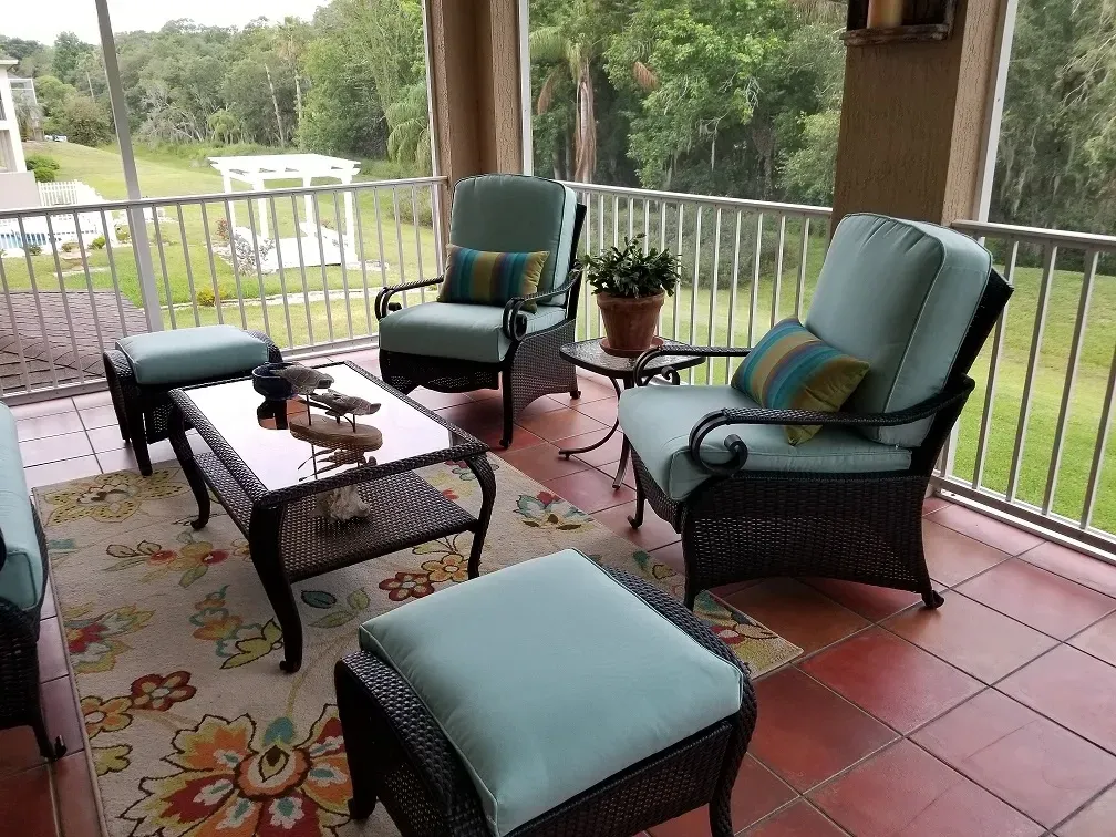 A screened in porch with wicker furniture and a rug