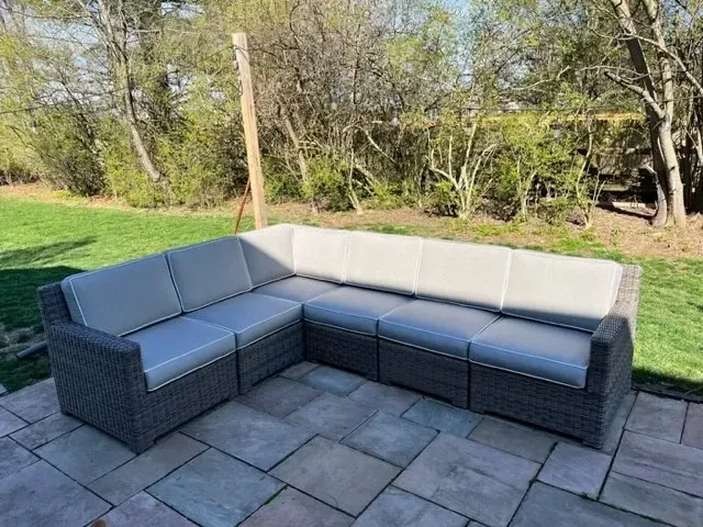A wicker sectional couch is sitting on a tiled patio.