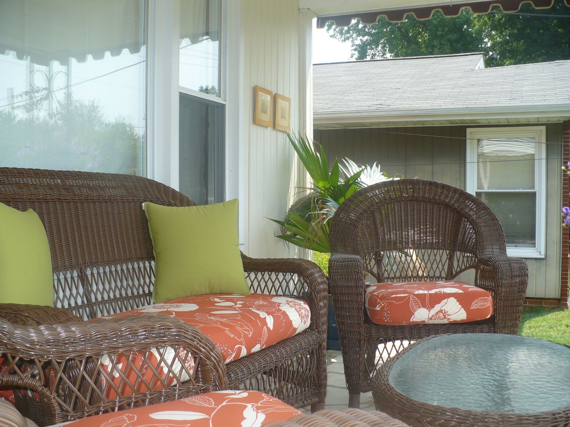 A porch with wicker furniture and a glass table