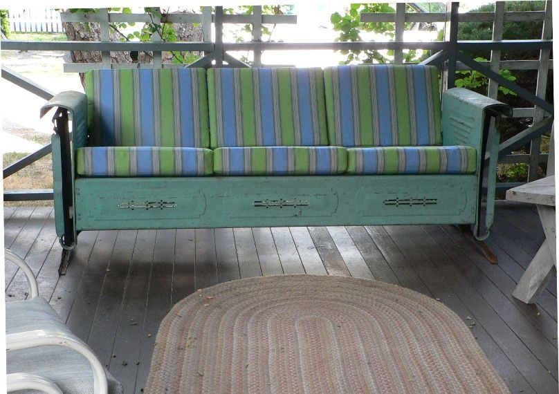 A porch swing with blue and green striped cushions