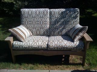 A couch with a pattern on it is sitting in the grass.