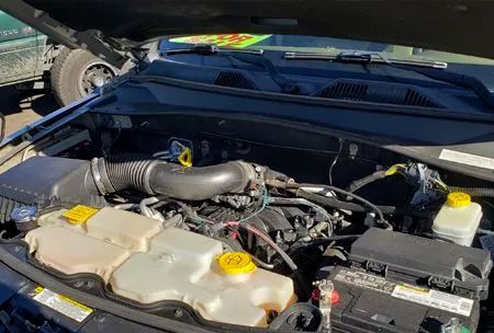 Black car engine bay with various components, including coolant reservoirs and air intake.