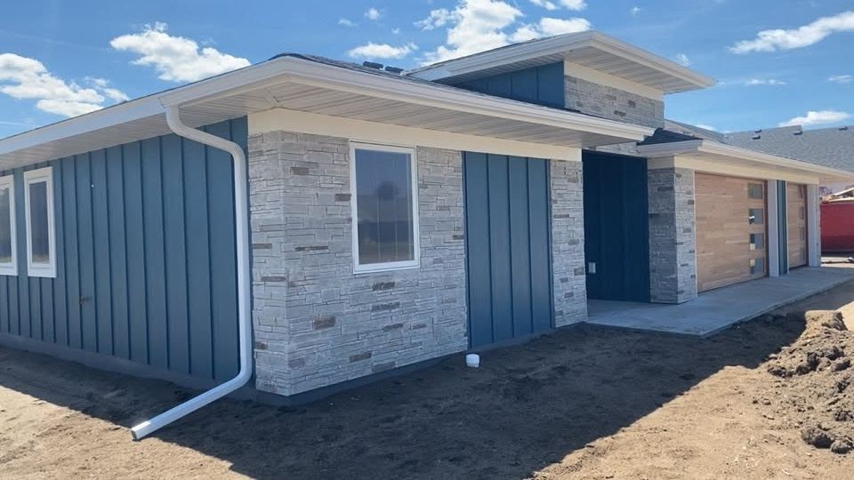 New single-story house with blue siding, white brick, and a covered front entry under construction.